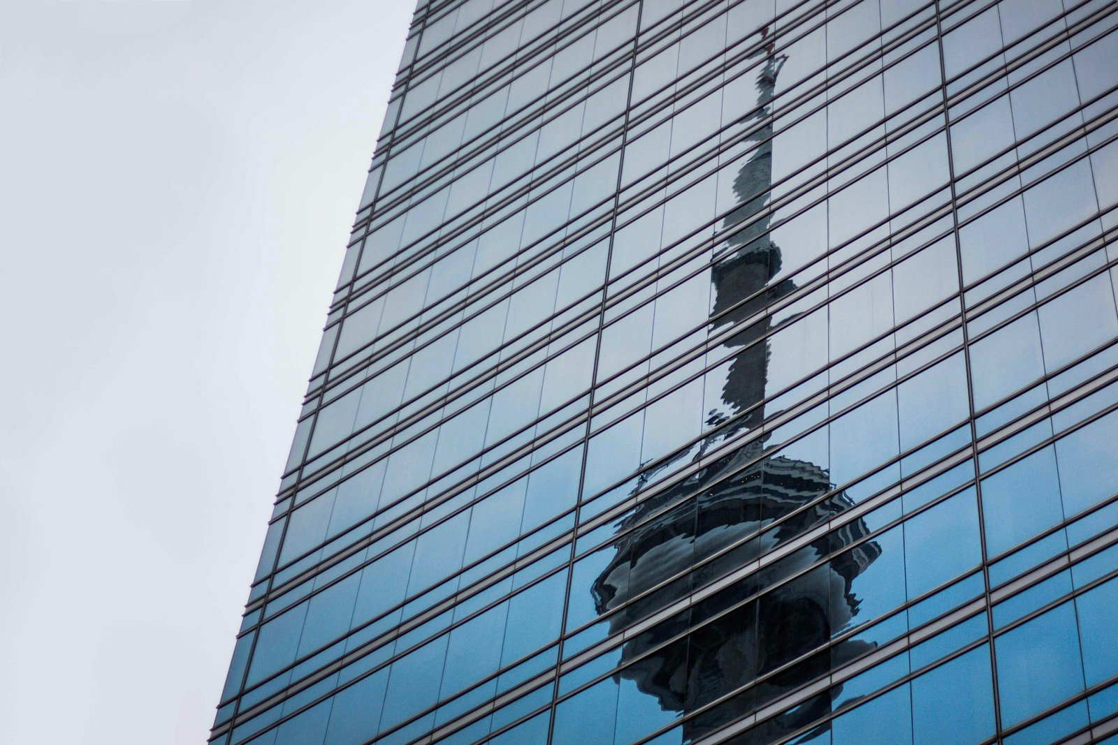 CN Tower reflected in a glass curtain wall façade in Toronto